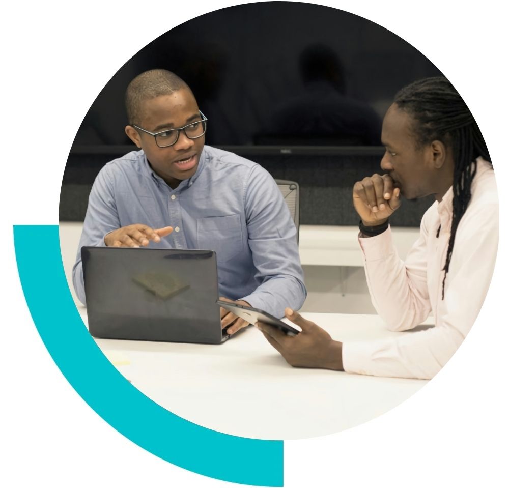 Two men in a meeting room in a coaching session talking to each other around a laptop